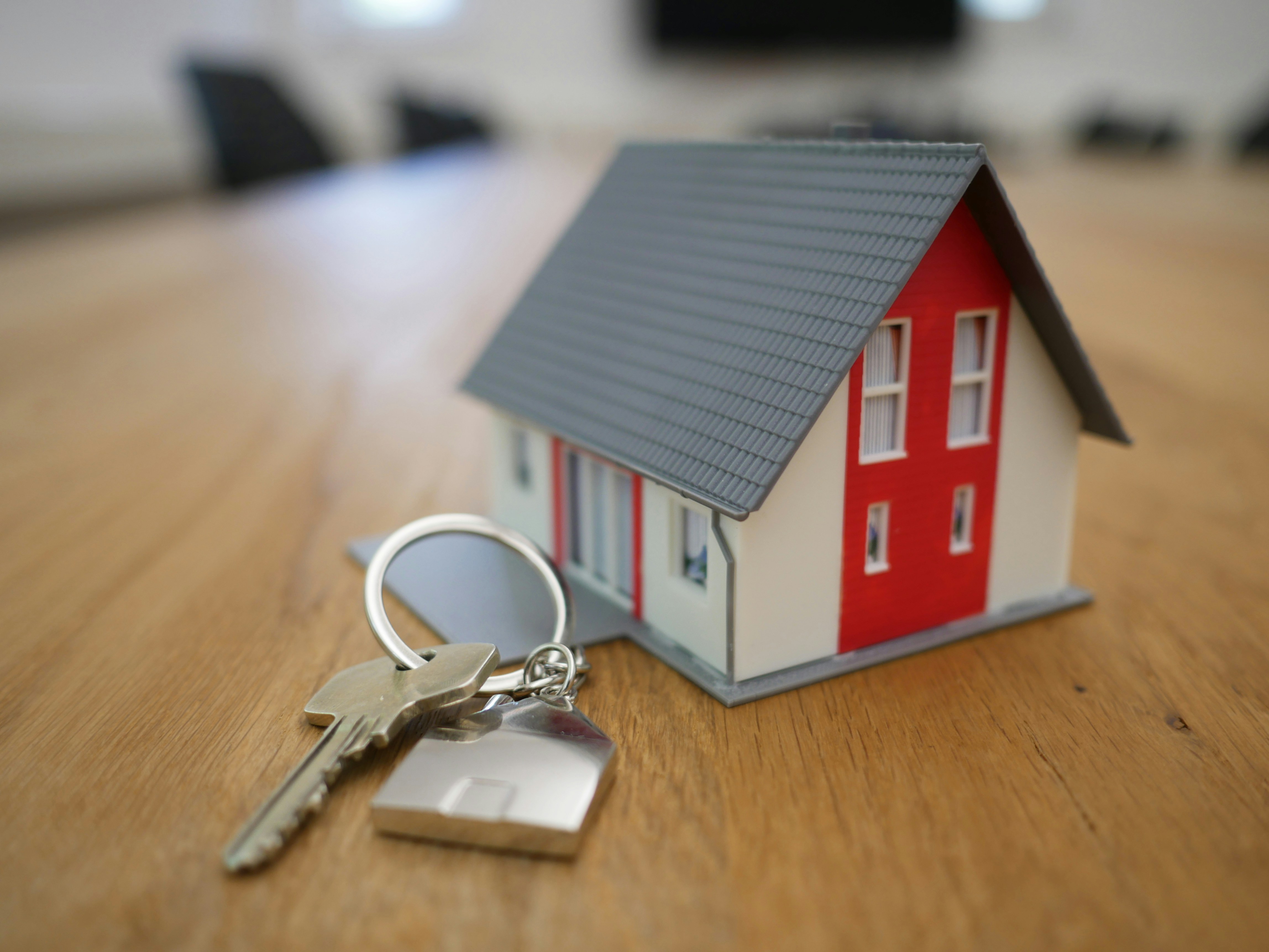 Small house figurine with a set of house keys next to it
